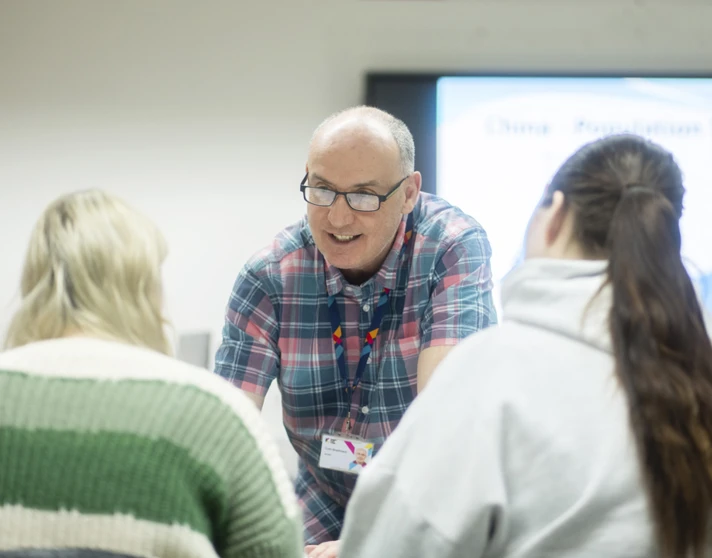 Smiling lecturer interacts closely with two students during a class at Glasgow Kelvin College. Smiling lecturer interacts closely with two students during a class at Glasgow Kelvin College.